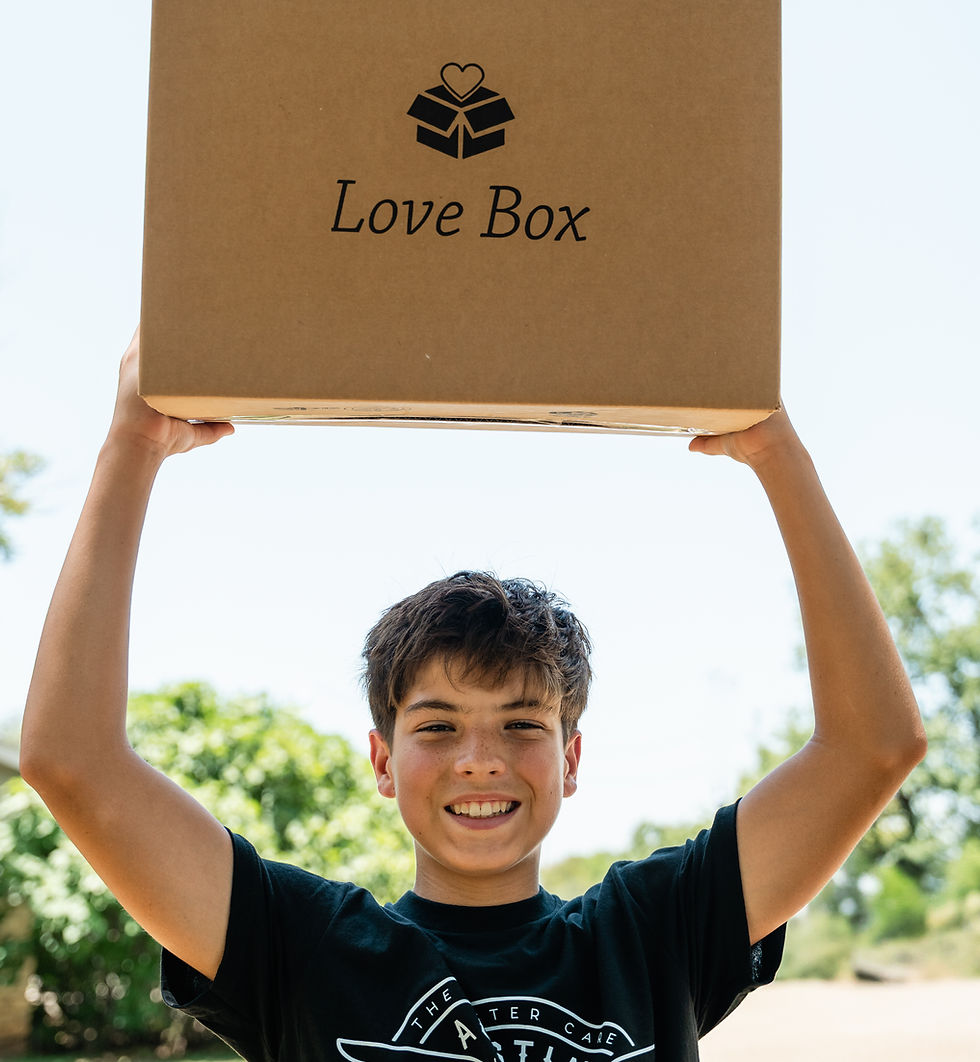 Child holding a cardboard Love Box overhead outdoors.